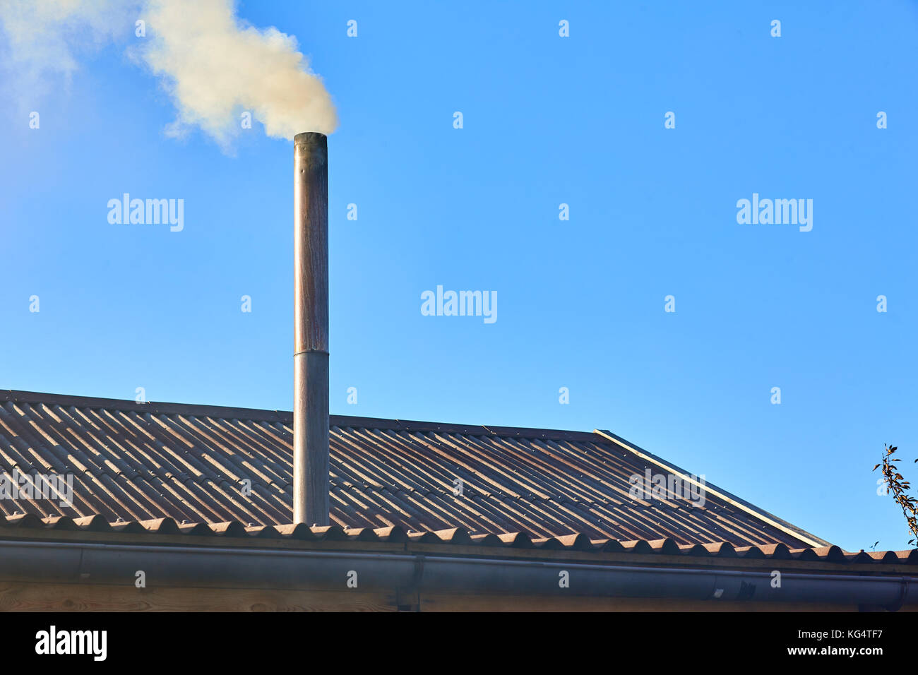 Smoke comes from the chimney of the house. The pipe on the roof