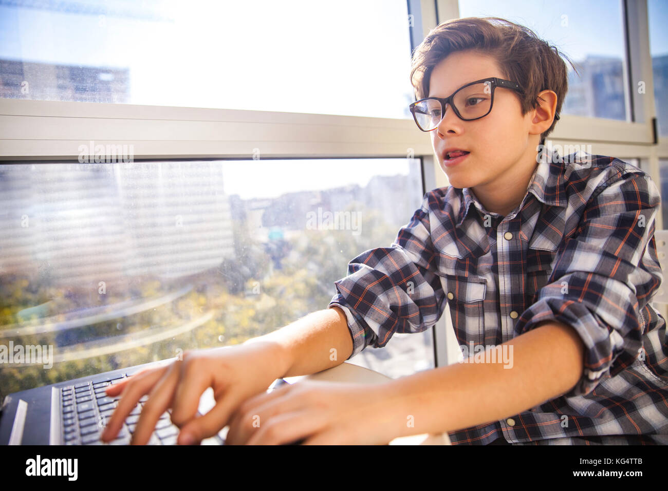 Portrait of teen boy using laptop by window Stock Photo - Alamy