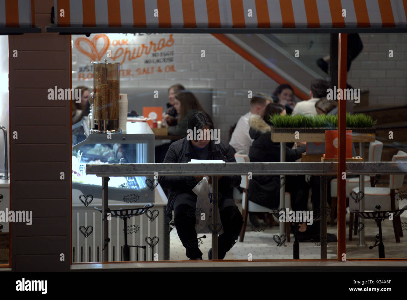 fast food restaurant window from the street cafe customers at night candid interior lit scene Stock Photo