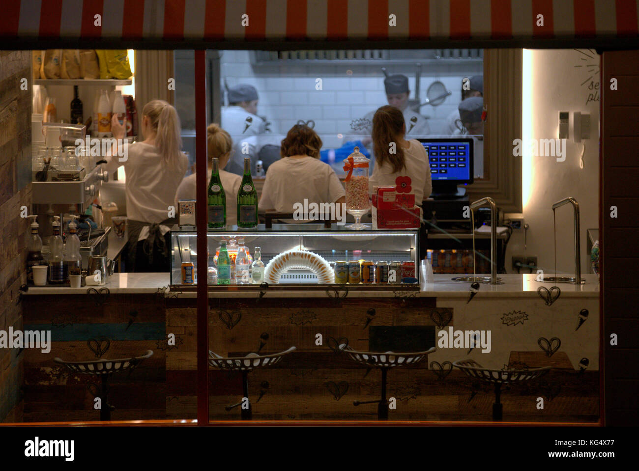 fast food restaurant staff workers window from the street cafe customers at night candid interior lit scene Stock Photo