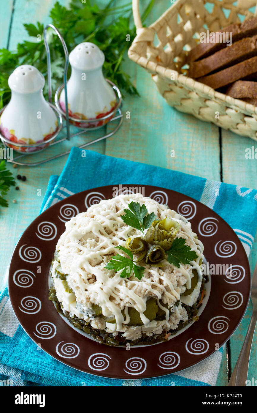 Home snack on the kitchen wooden table. Salad with chicken, rice and sea cabbage. Stock Photo