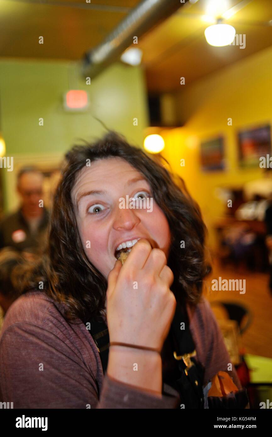 Woman taking a bite out of cookie, wearing a wild expression on her face. Stock Photo