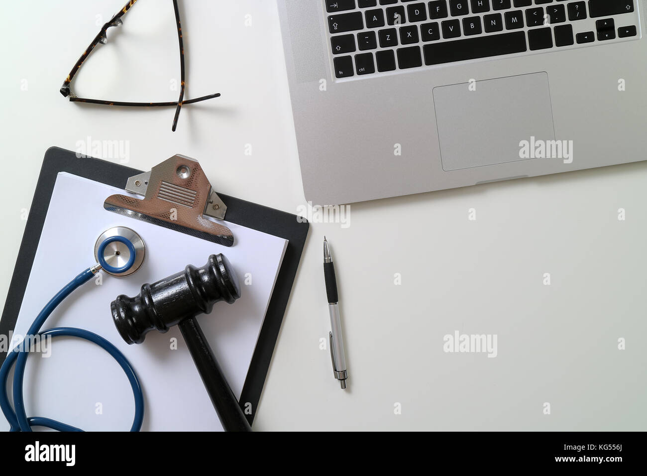Dark Gavel With Medical Stethoscope near Laptop on white desk In Courtroom concept Stock Photo