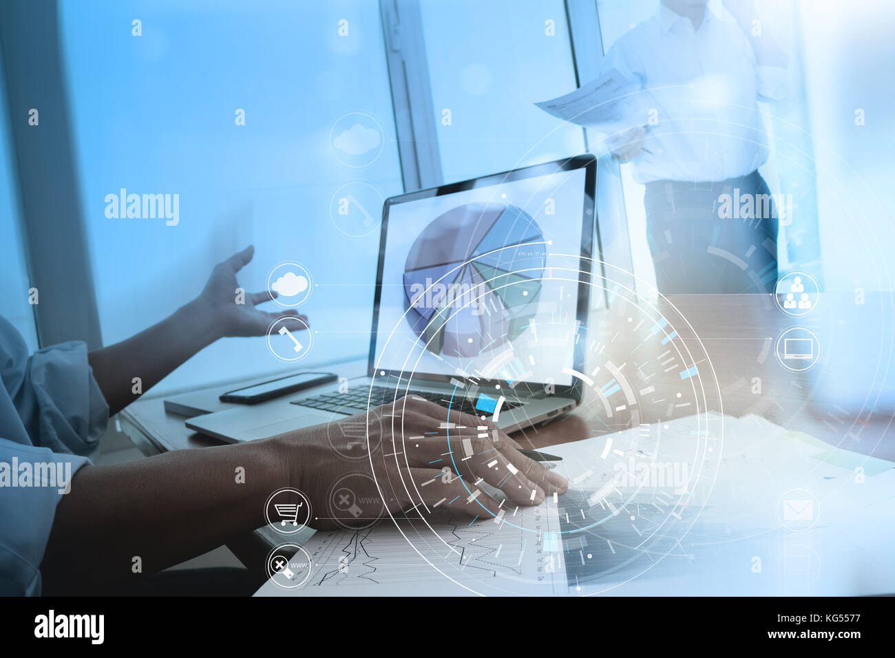 Hands of businessman using mobile phone in modern office with laptop and digital tablet computer in team meeting with VR icon diagram Stock Photo