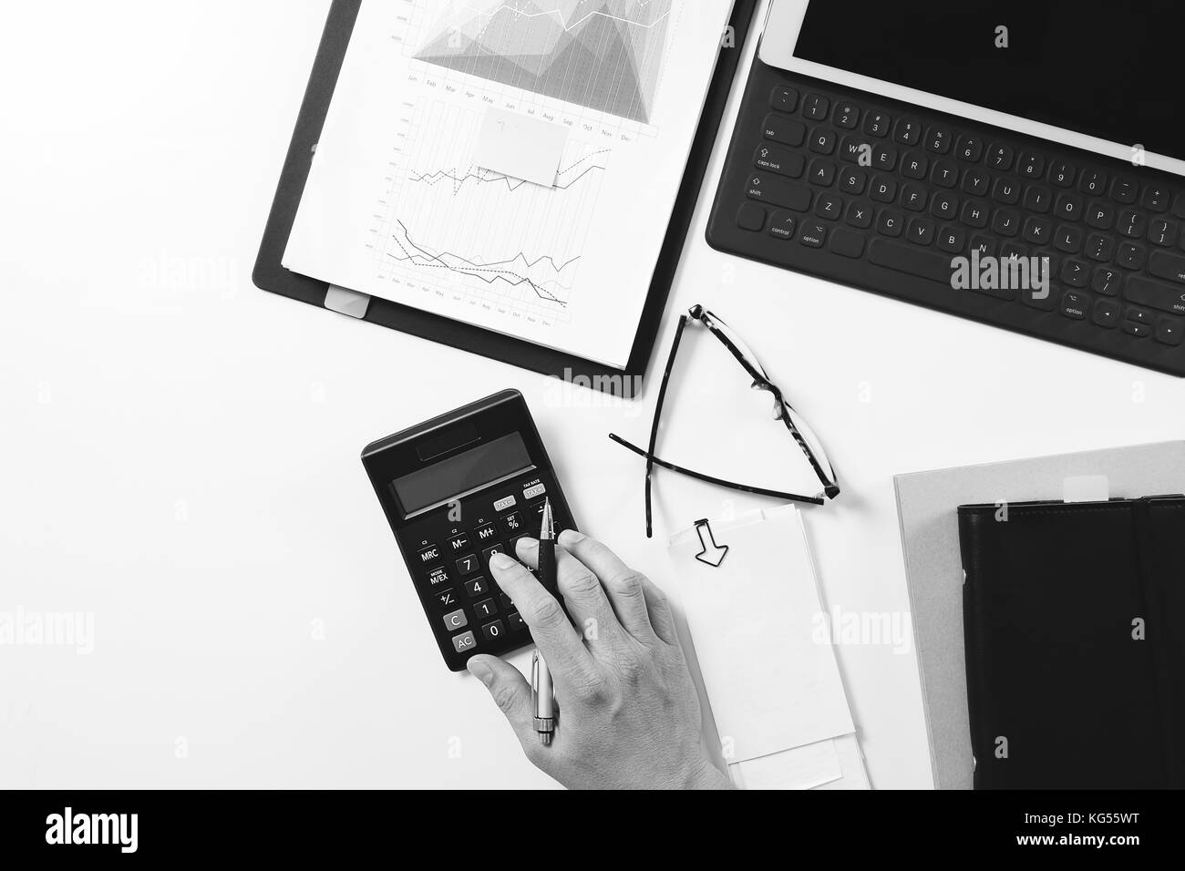 top view of businessman hand working with finances about cost and calculator and latop with mobile phone on withe desk in modern office,black and whit Stock Photo