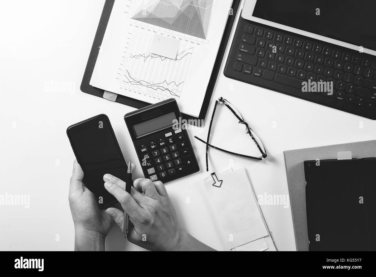 top view of businessman hand working with finances about cost and calculator and latop with mobile phone on withe desk in modern office ,black with wh Stock Photo