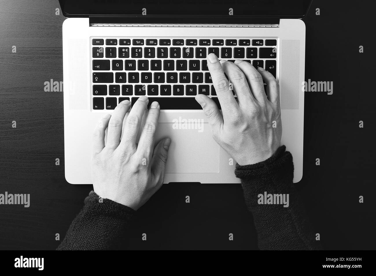 top view of businessman typing keyboard with laptop computer on wooden desk in modern office,black and white Stock Photo