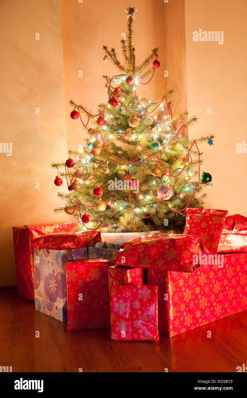 Christmas tree with lights and presents in dark room Stock Photo