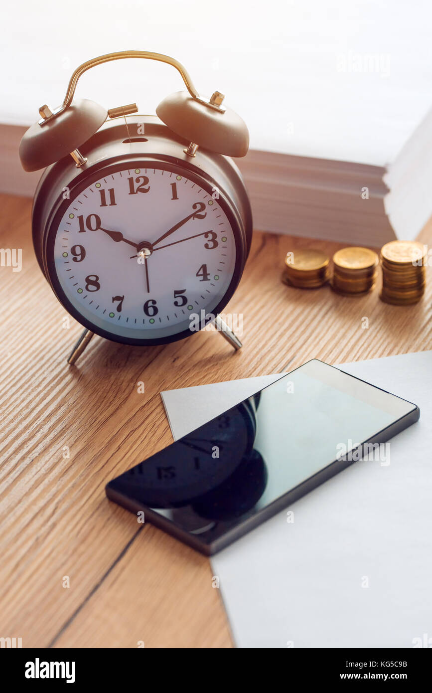 Working hours, vintage clock and mobile phone on business office desk Stock Photo