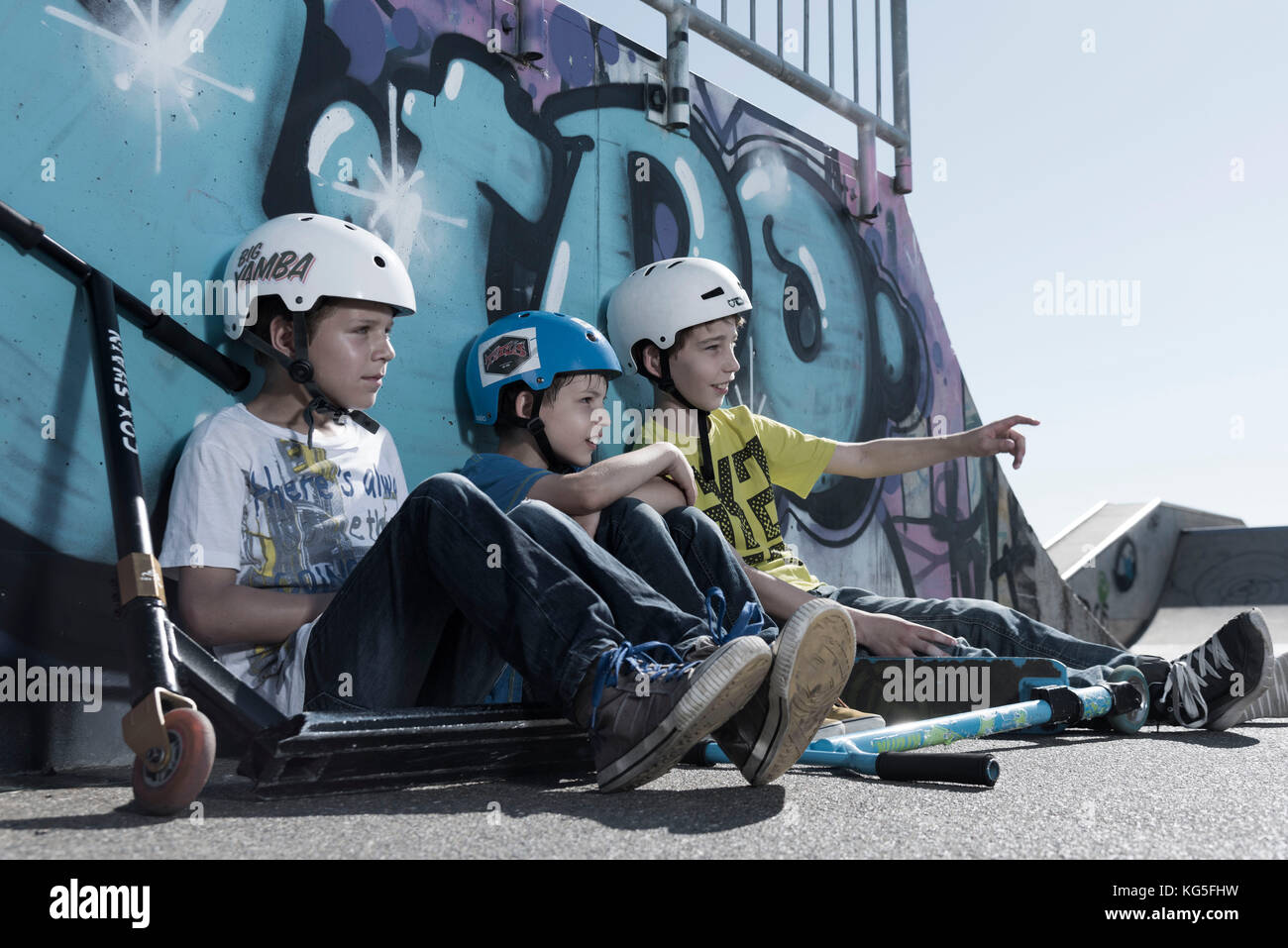 Three boys with Scooter in the skate park Stock Photo