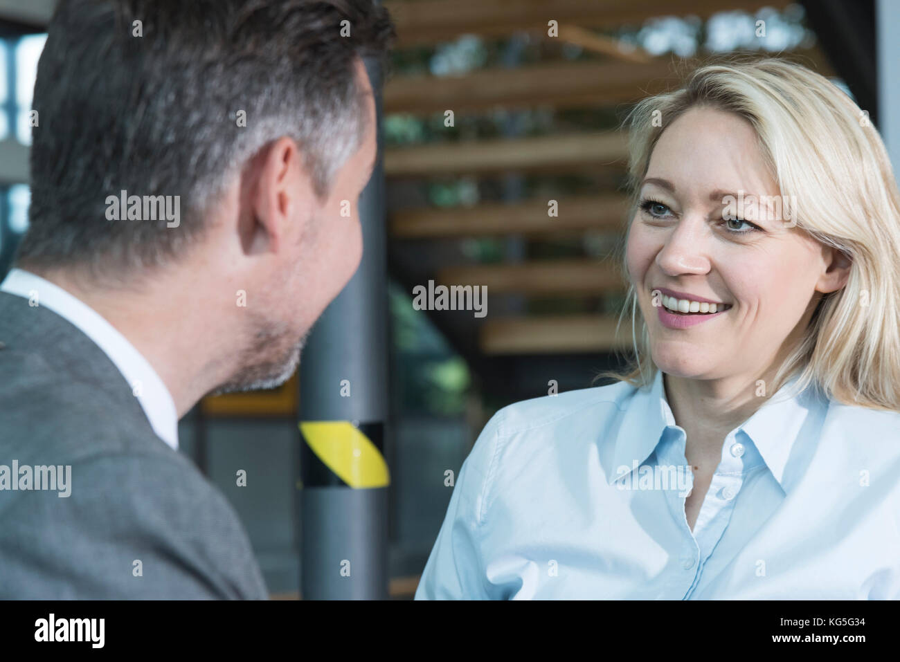 Businessman in the conversation with the businesswoman, shot over the shoulder of the man Stock Photo