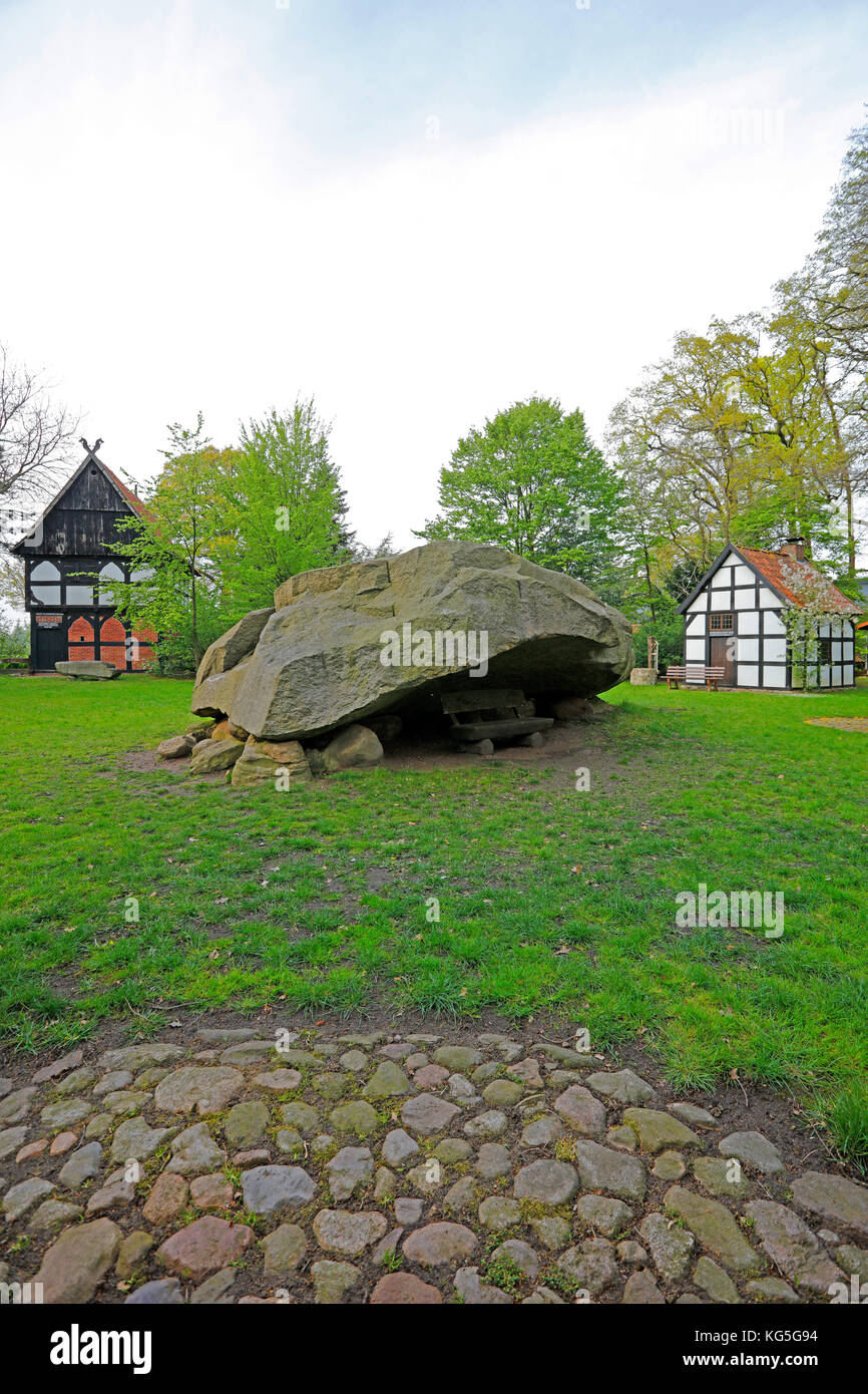 the big erratic block of Tonnenheide in an oak forest with half-timbered houses on Westfälischen Mühlenstraße (route), Germany, administrative district of Minden-Lübbecke Stock Photo