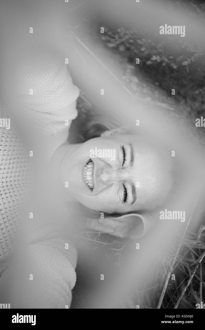 young woman smiling in nature, holding hand in front of camera, b / w Stock Photo