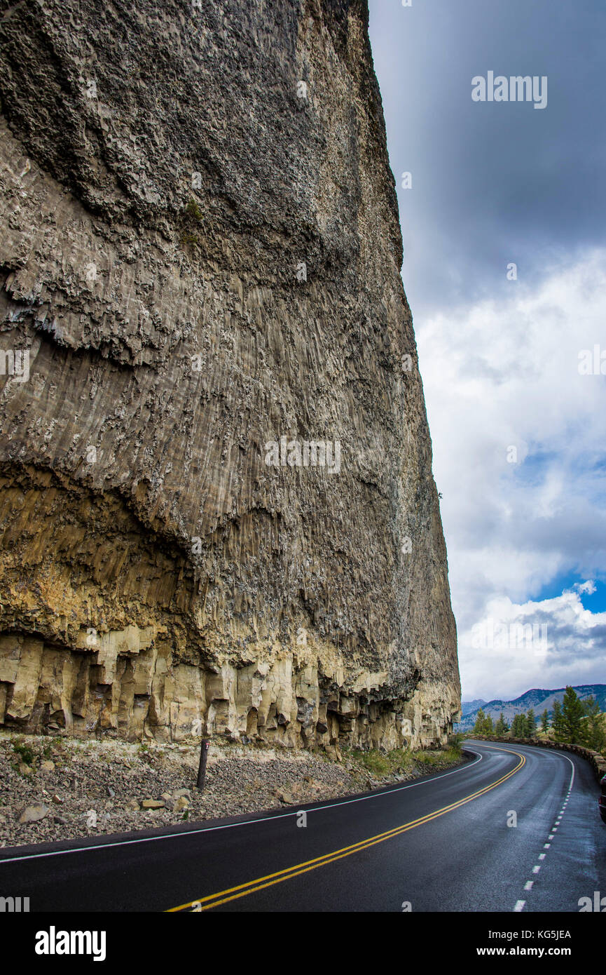 Highway below a huge stone wall Yellowstone National Park, Wyoming, USA Stock Photo