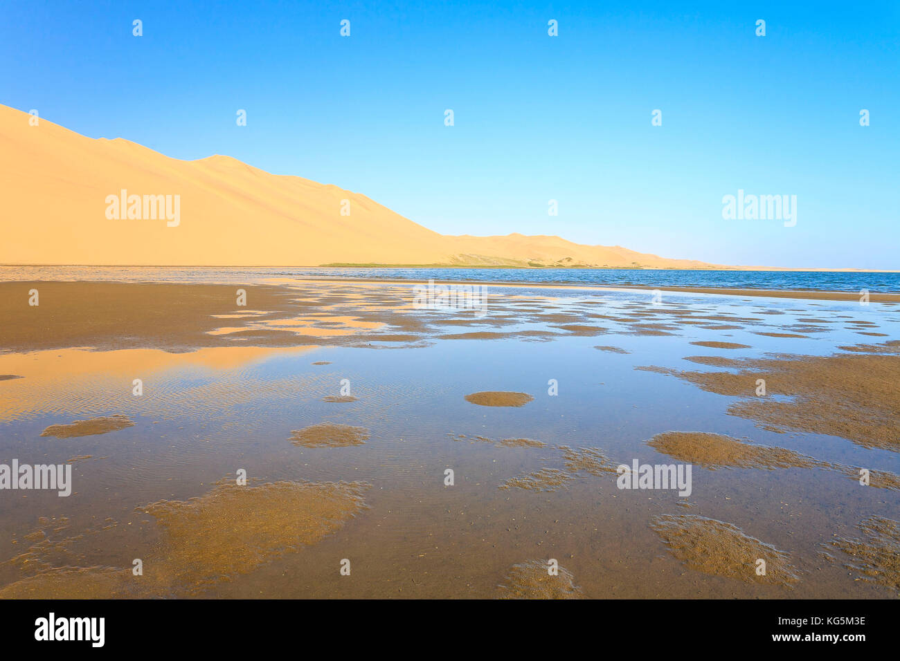 Sand dunes reflected in the lagoon beside the Atlantic Ocean Walvis Bay Namib Desert Erongo Region Namibia Southern Africa Stock Photo