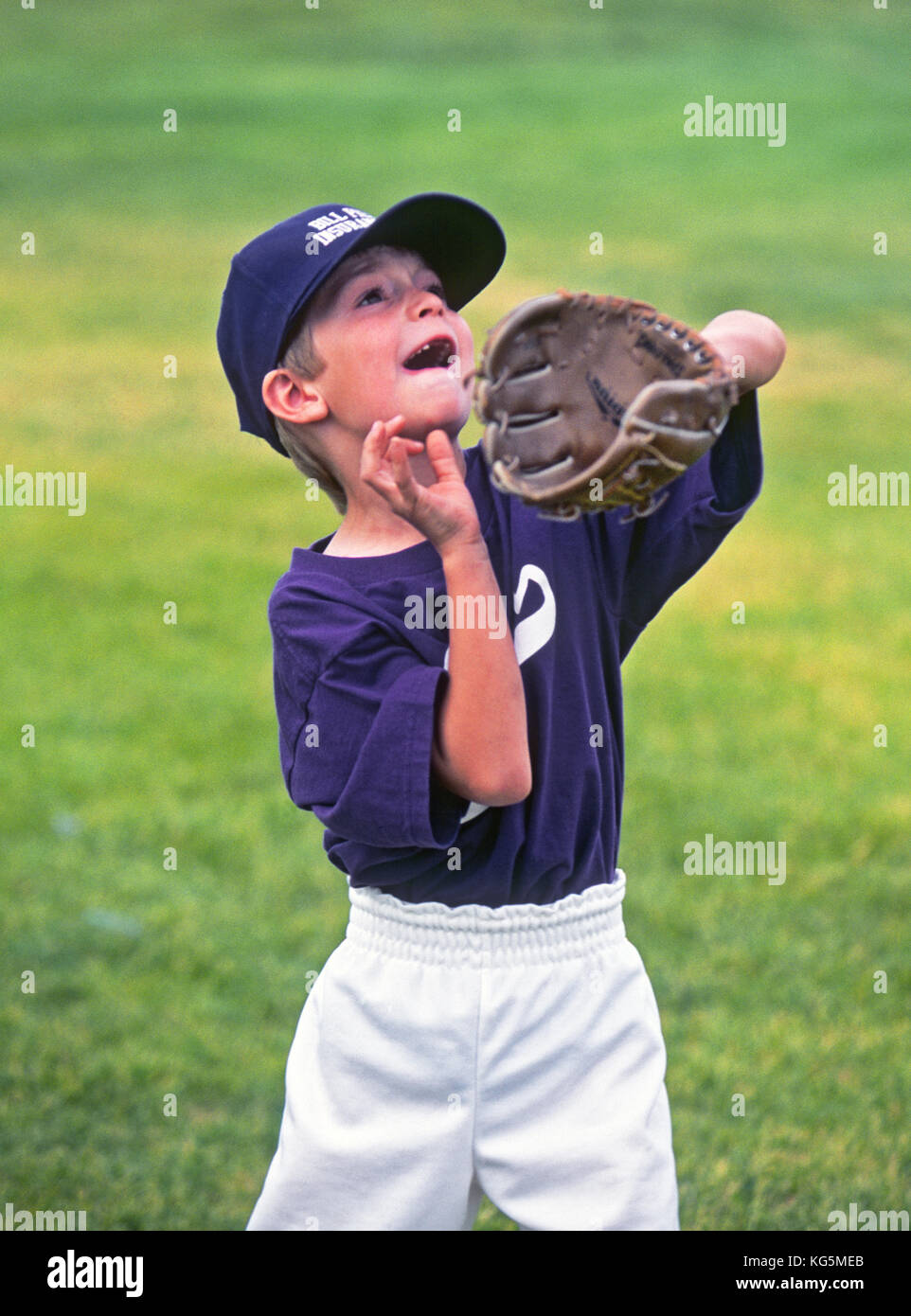 A young boy playing Little League Baseball, prepares to catch a pop fly ball. Stock Photo