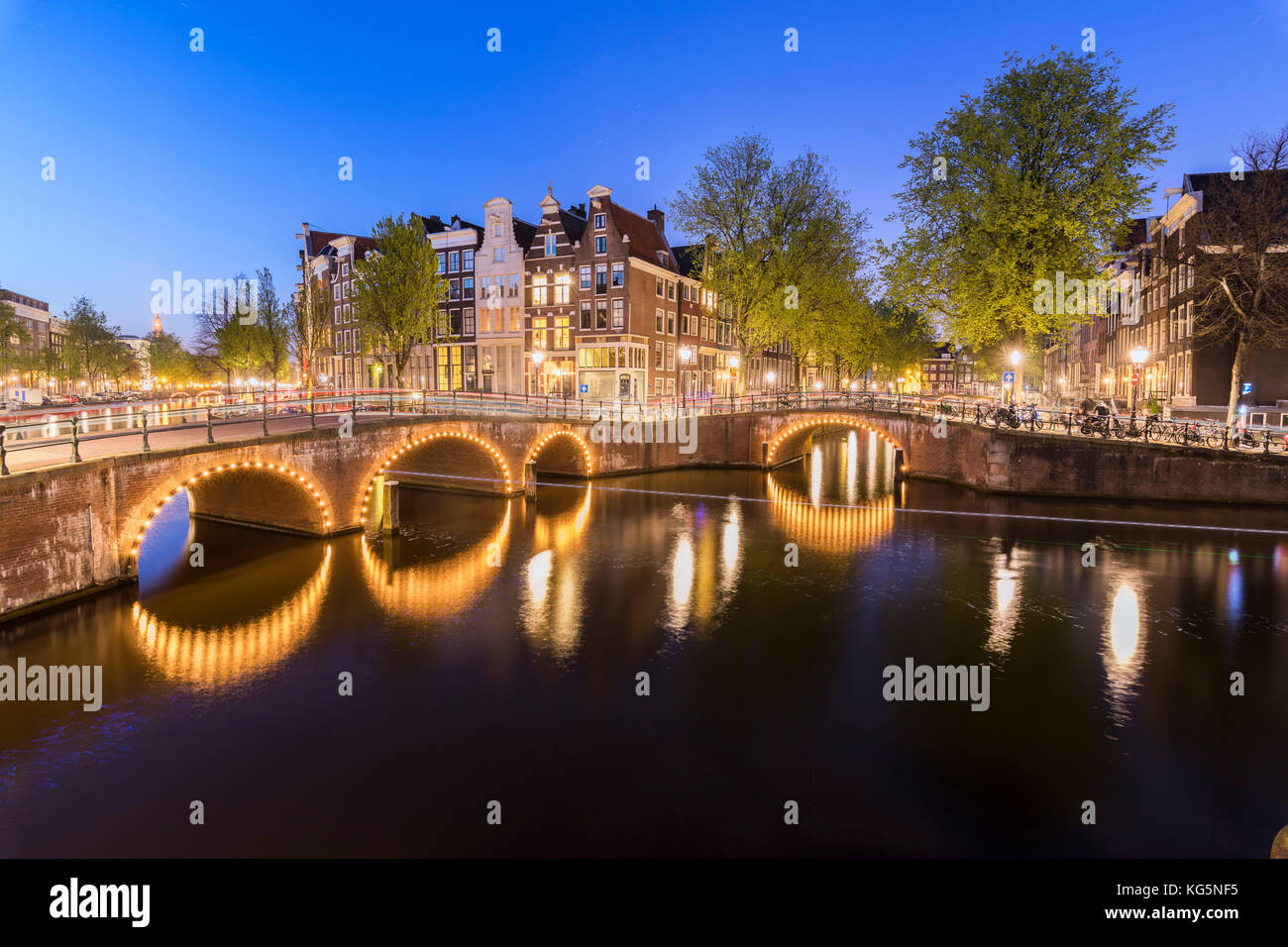 Dusk lights on the typical buildings and bridges reflected in a typical canal Amsterdam Holland The Netherlands Europe Stock Photo