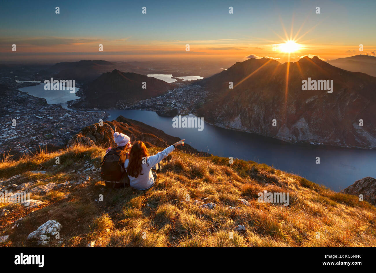 Lake Como, Lombardy, Italy. Two friends watching a scenic sunset from above Lecco city. Stock Photo