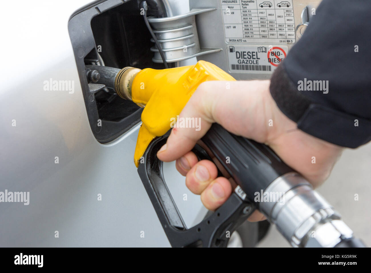 Valenciennes, France. 19 March 2017. A man holding a yellow filling nozzle (gun) and is filling gas to a car. Stock Photo