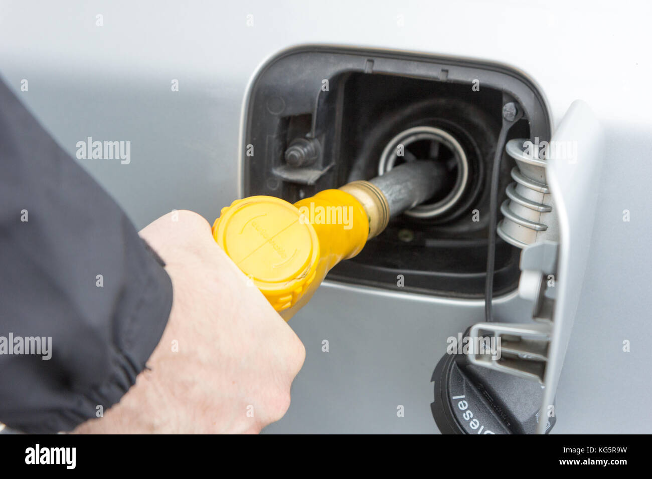 Valenciennes, France. 19 March 2017. A man holding a yellow filling nozzle (gun) and is filling gas to a car. Stock Photo