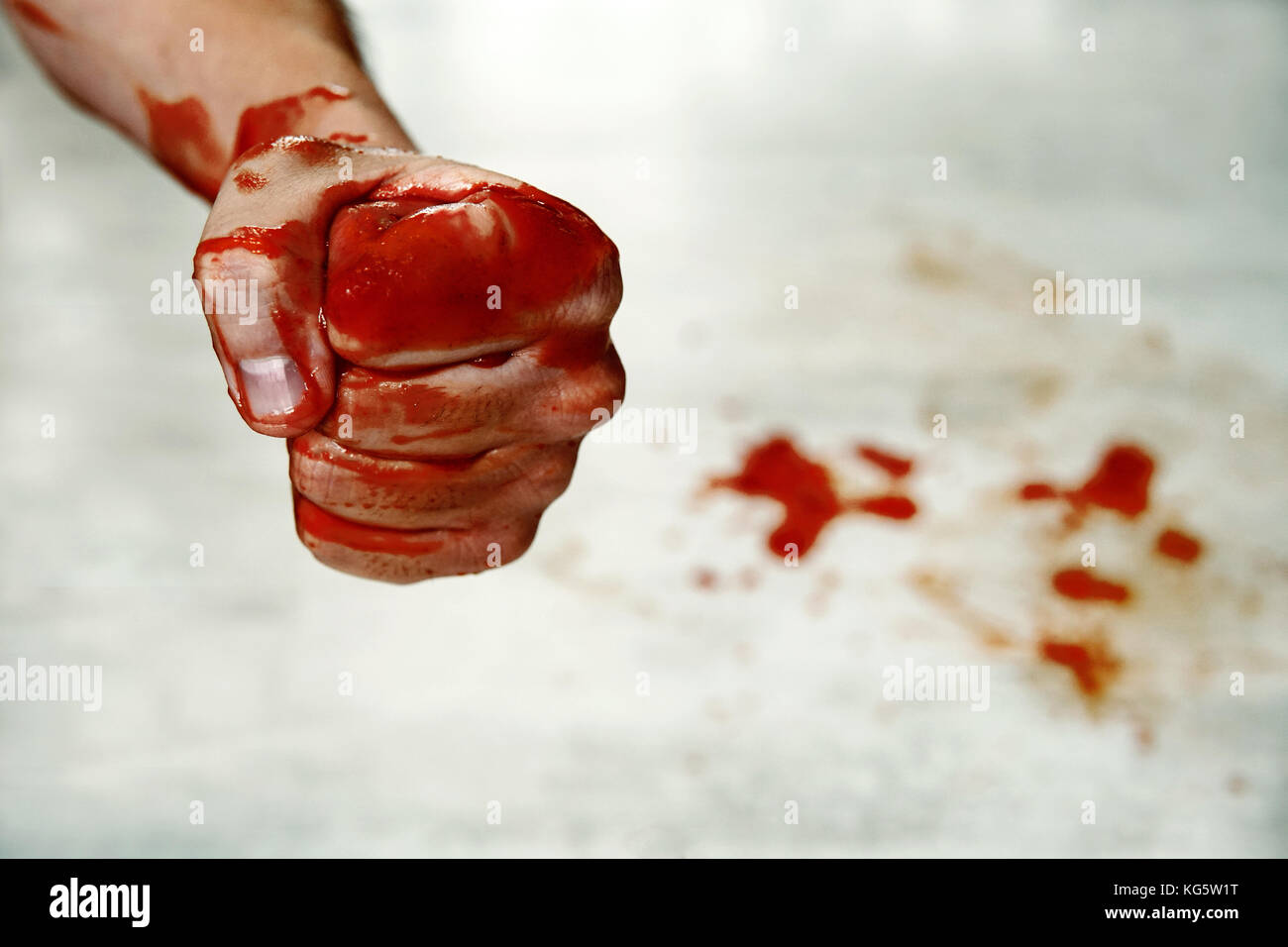 Fists with blood. Fighter. Fist blood closeup on the background of the drops of blood on the floor. Fighter fighter shows a bloody hand folded in a fi Stock Photo