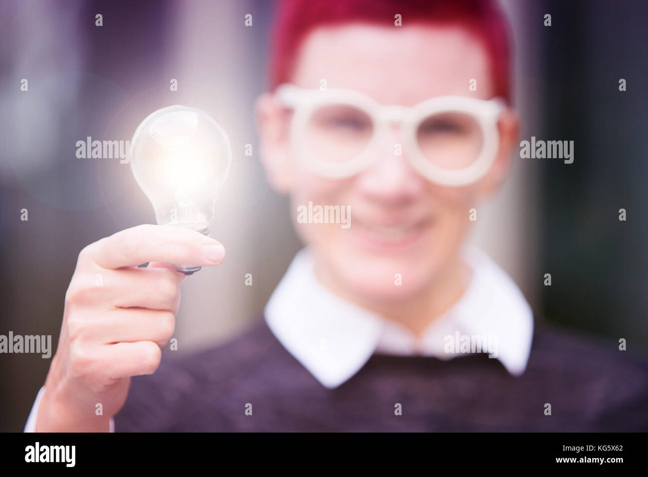 portrait of red-haired woman holding a glowing lightbulb Stock Photo