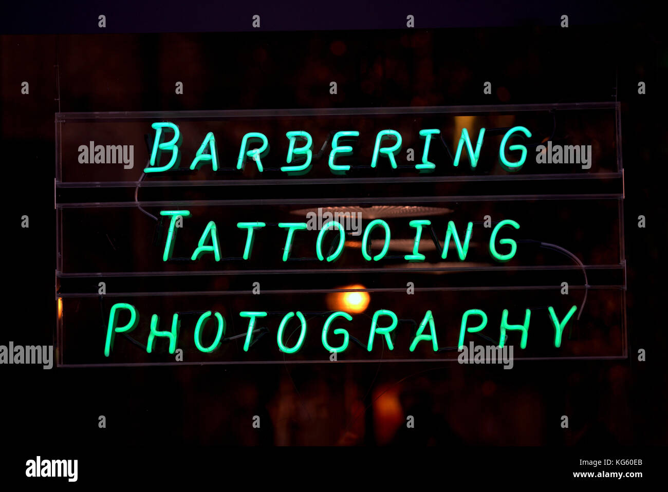 barbering tattooing photography neon sign  shop window photographed from public street Stock Photo