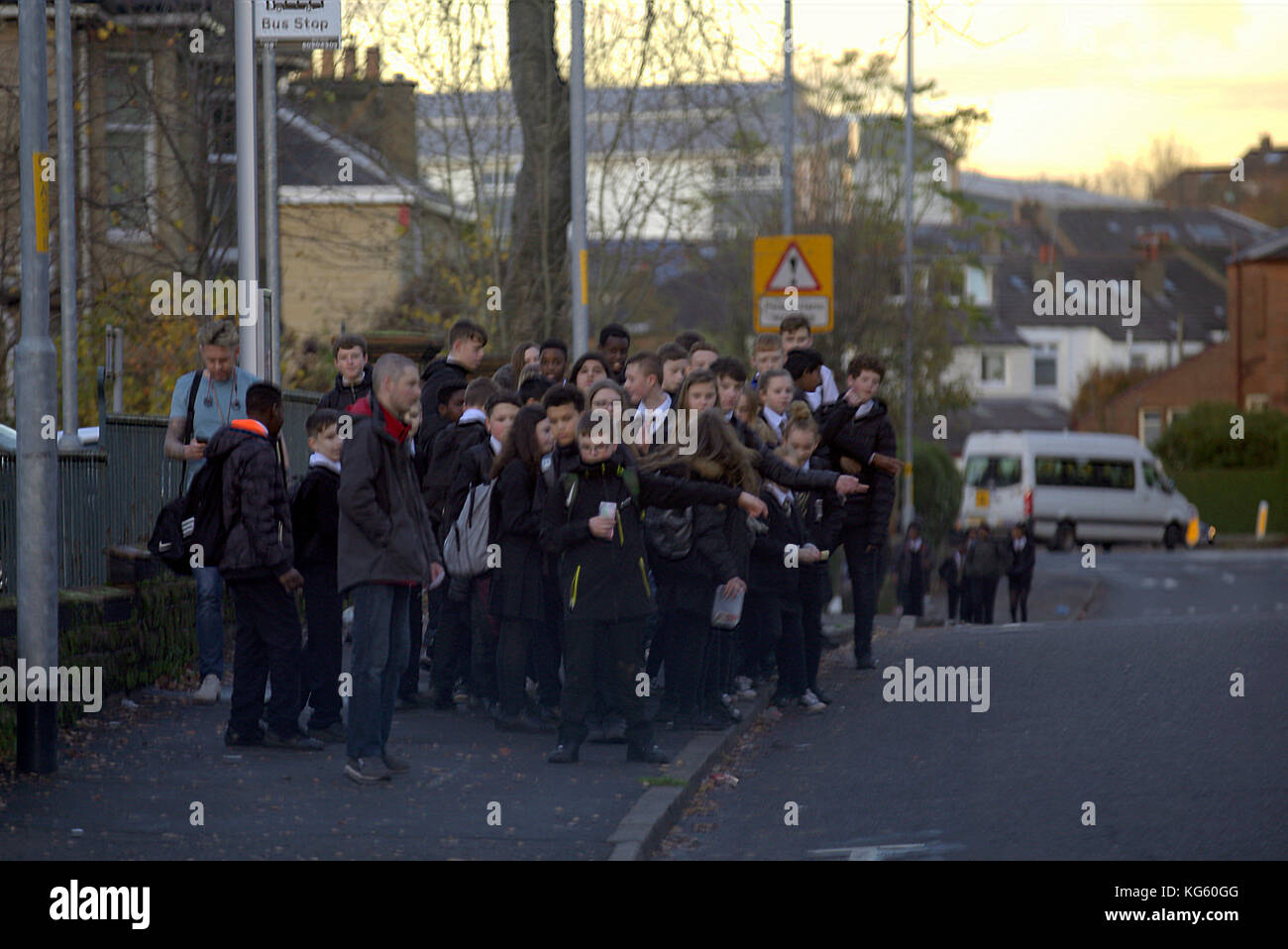 large group schoolchildren at bus stop signal request to board  street Jordanhill news image Stock Photo