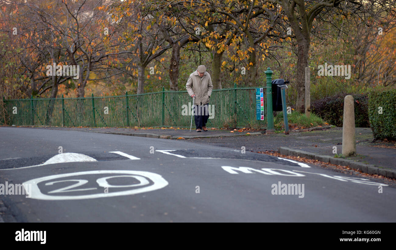 old man senior oap walking along street in perspective road slow markings  20 mph speed limit and speed humps ironic funny ha ha Stock Photo