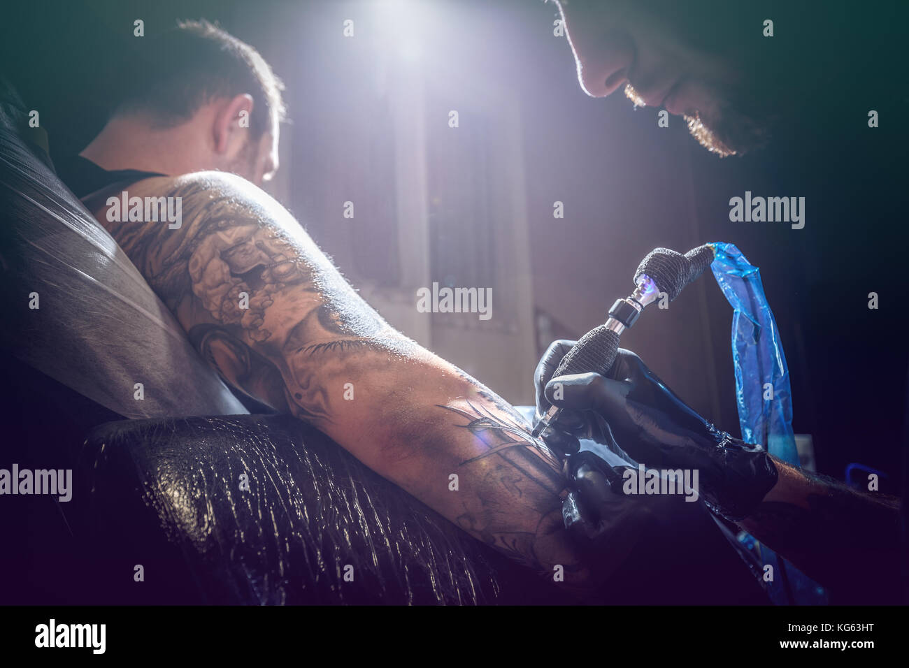 Portrait of a man tattoo master showing a process of tattoo creation in ...