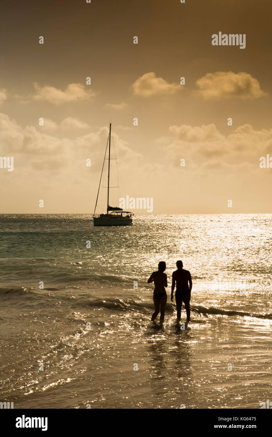 The Seychelles, Praslin, Anse Georgette, beach couple silhouetted in sea at sunset Stock Photo