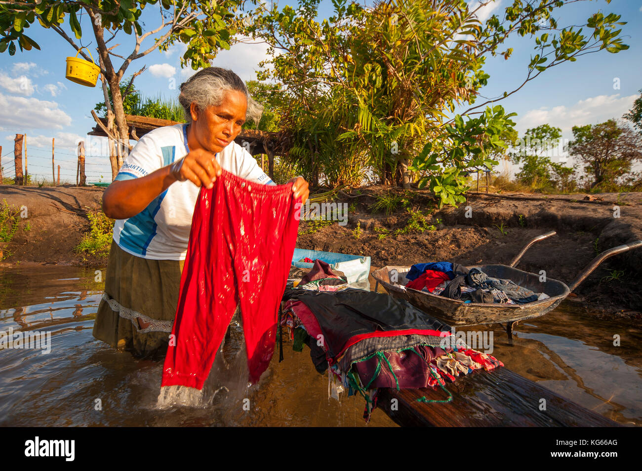 Old woman inabitant of remote area of Fumaça waterfall in Tocantins estate washing clothes in Balsas River, Brazil Stock Photo