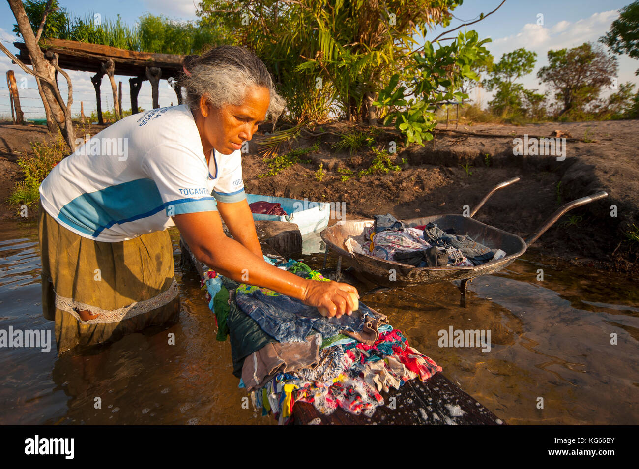 Old woman inabitant of remote area of Fumaça waterfall in Tocantins estate washing clothes in Balsas River, Brazil Stock Photo