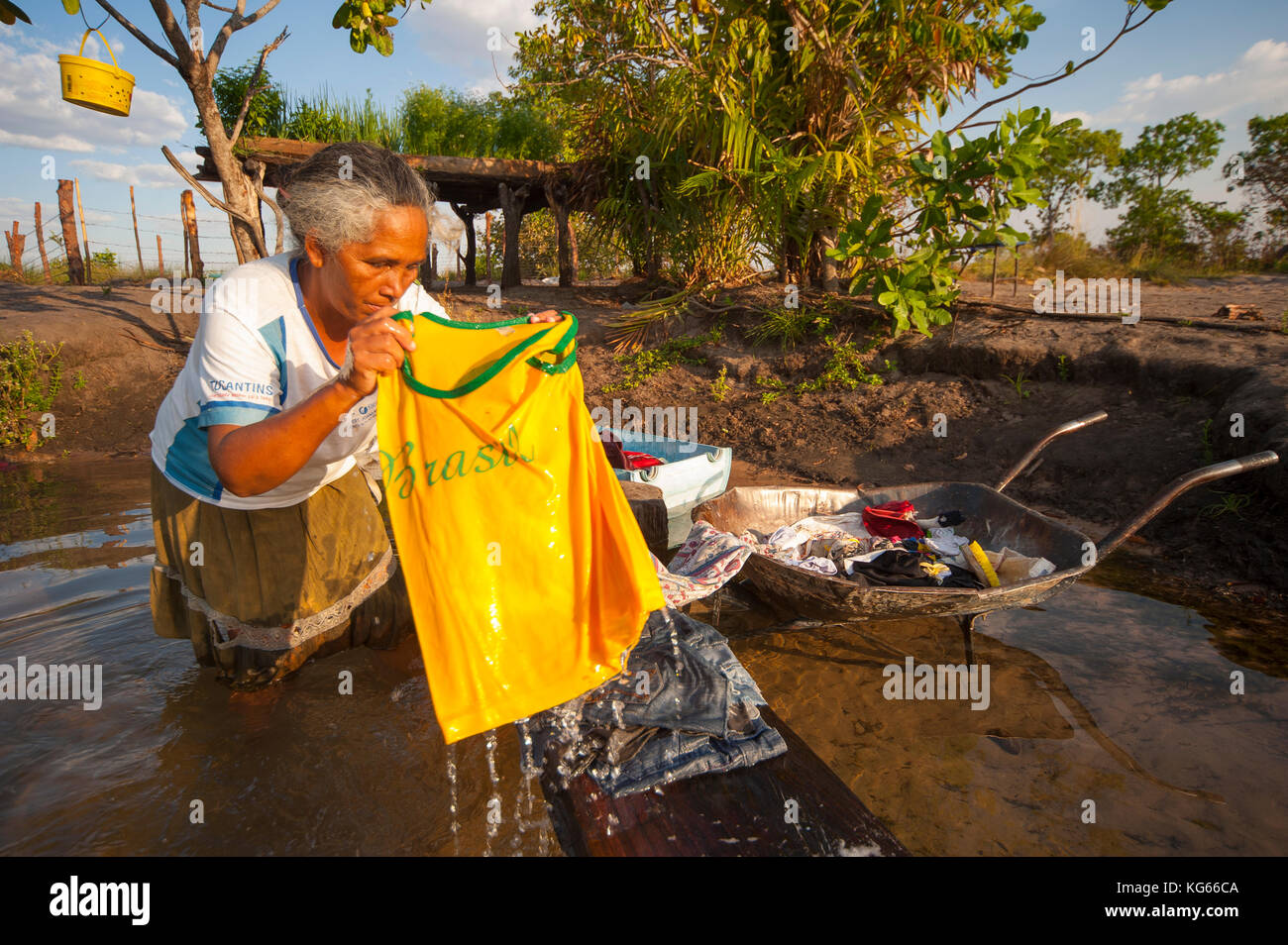 Old woman inabitant of remote area of Fumaça waterfall in Tocantins estate washing clothes in Balsas River, Brazil Stock Photo