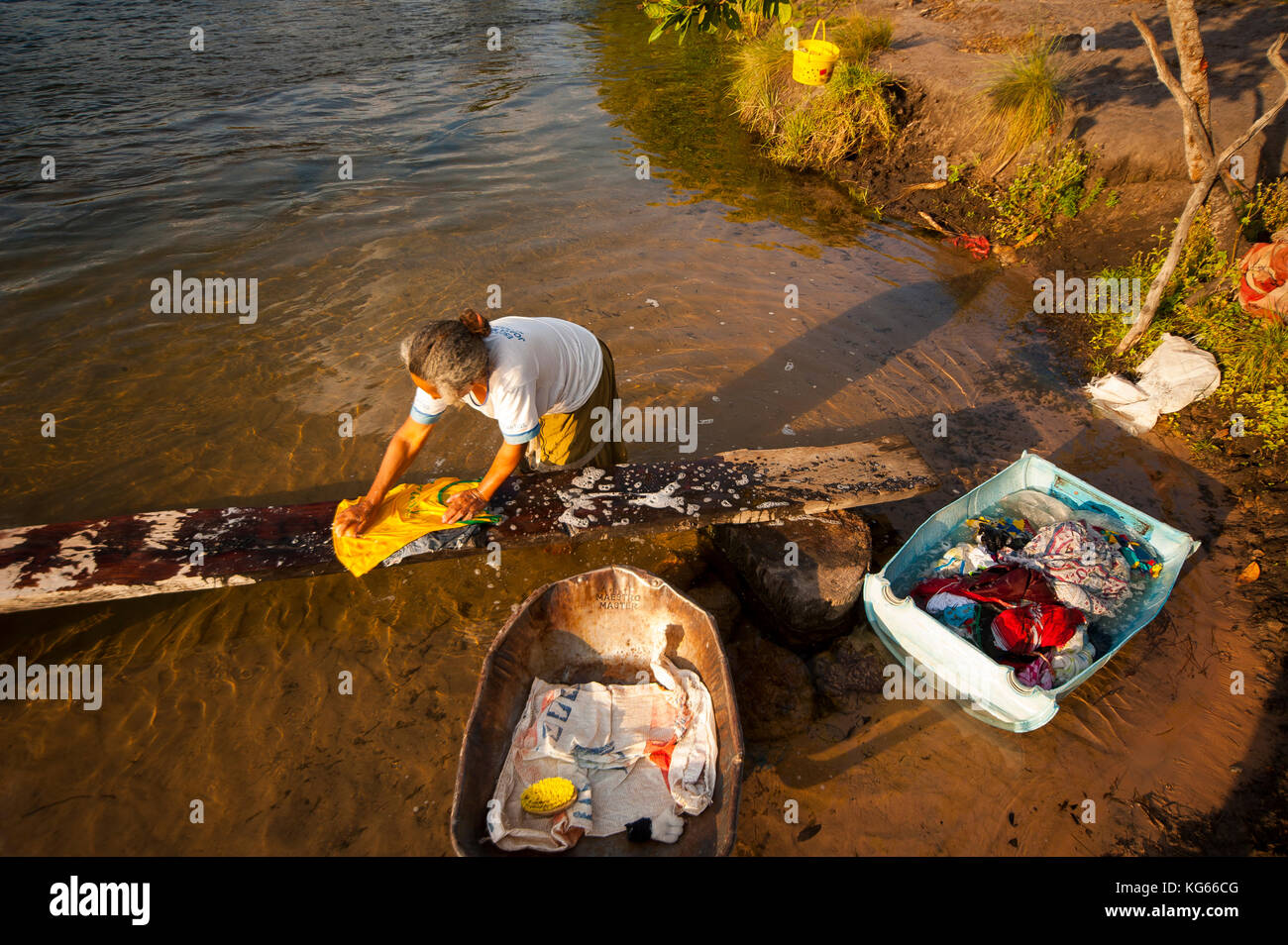 Old woman inabitant of remote area of Fumaça waterfall in Tocantins estate washing clothes in Balsas River, Brazil Stock Photo