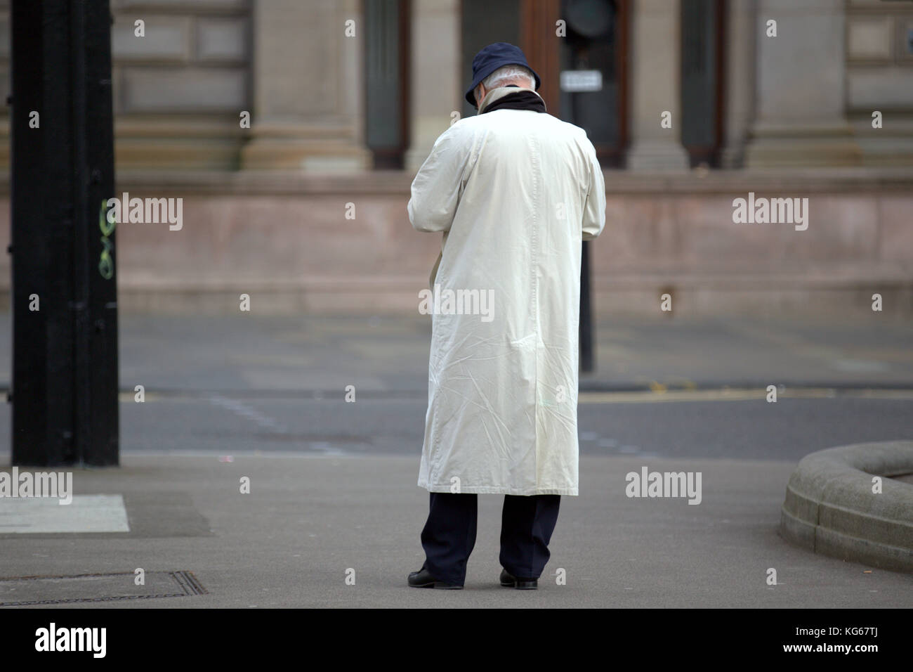 man in white raincoat  viewed from behind Stock Photo
