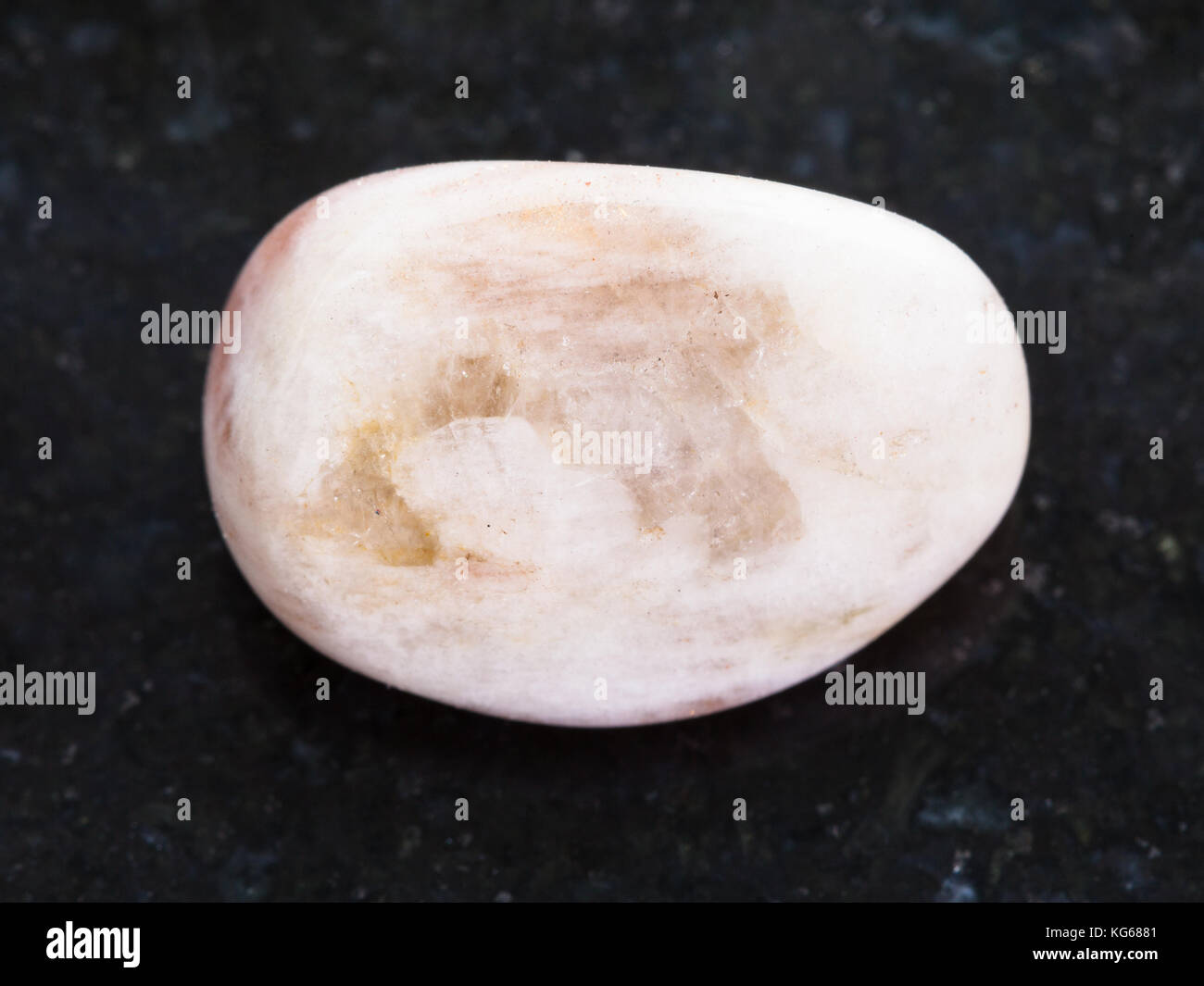 macro shooting of natural mineral rock specimen - polished moonstone gemstone on dark granite background Stock Photo