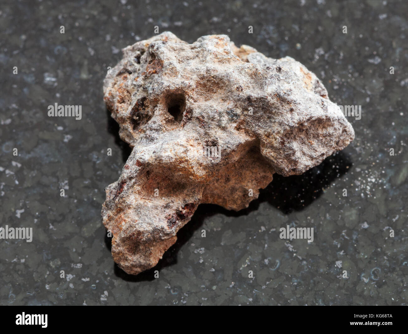 macro shooting of natural mineral rock specimen - rough Basalt stone on dark granite background Stock Photo