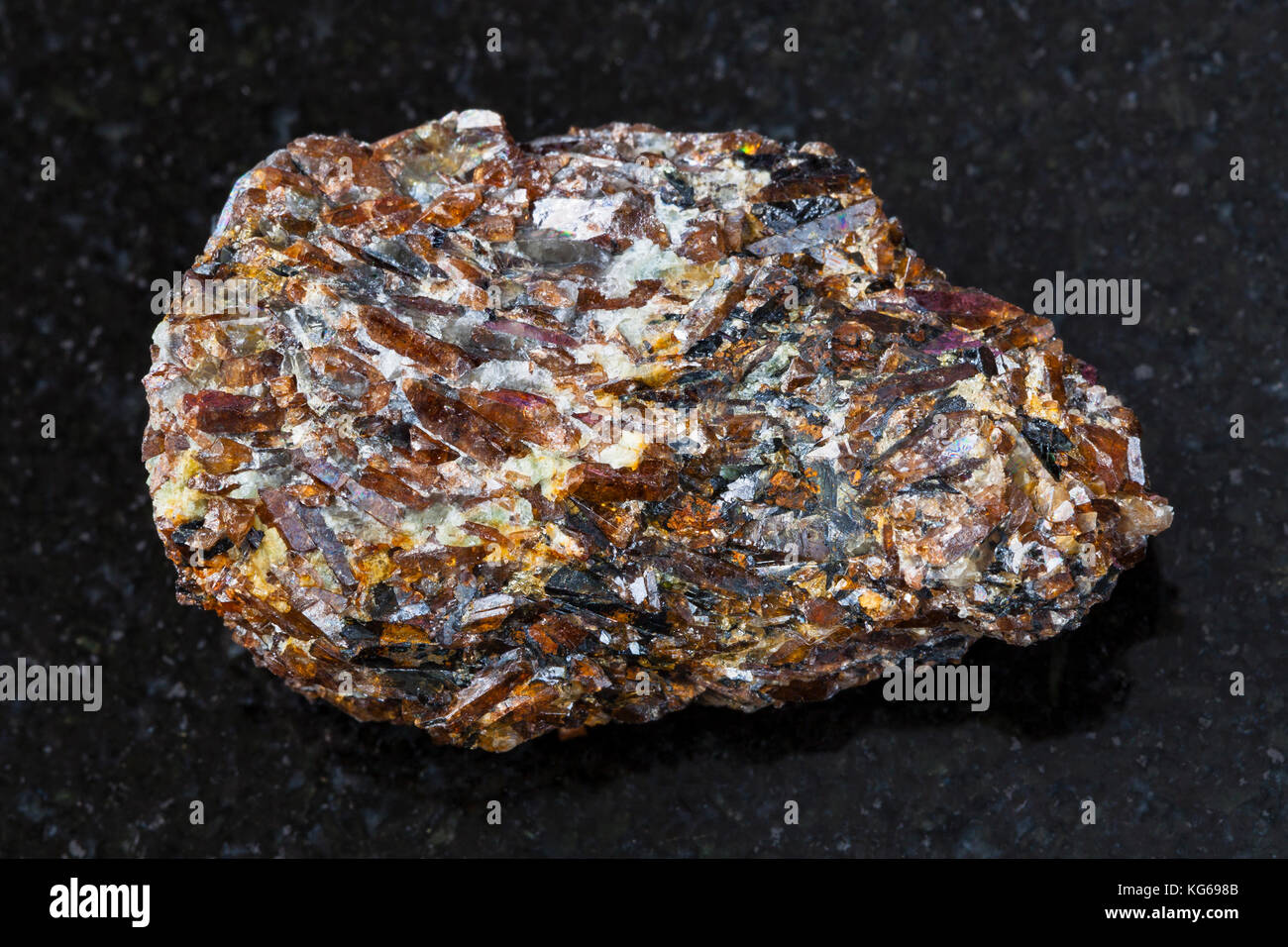 macro shooting of natural mineral rock specimen - rough Titanite stone on dark granite background from Khibiny Mountains, Kola Peninsula, Russia Stock Photo