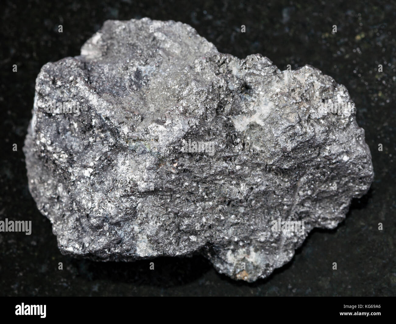 macro shooting of natural mineral rock specimen - raw Graphite stone on dark granite background from Bogotol region of Eastern Sayan Mountains, Russia Stock Photo