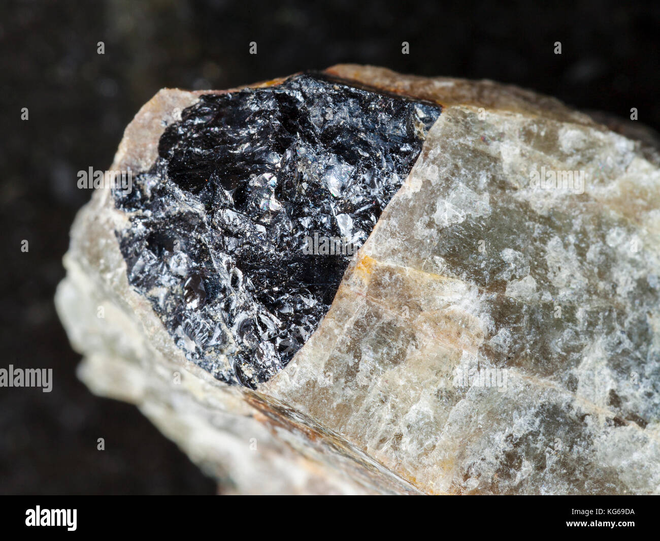 macro shooting of natural mineral rock specimen - black Ilmenite in rough green Nepheline stone on dark granite background from Krasnoyarsk Krai, Russ Stock Photo