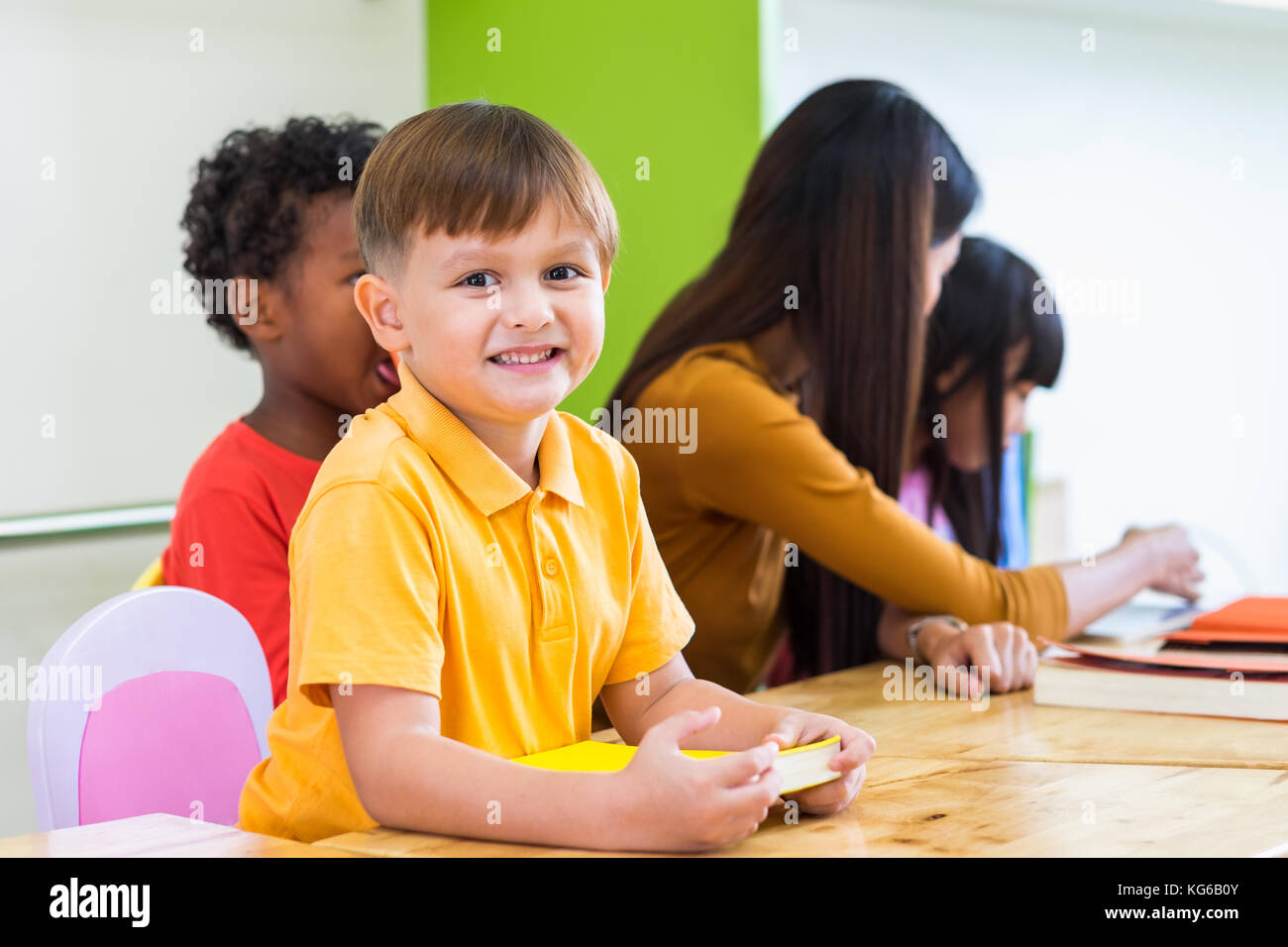 Caucasian boy ethnicity kid smiling white learning in classroom with friends and teacher  in kindergarten school, education concept Stock Photo