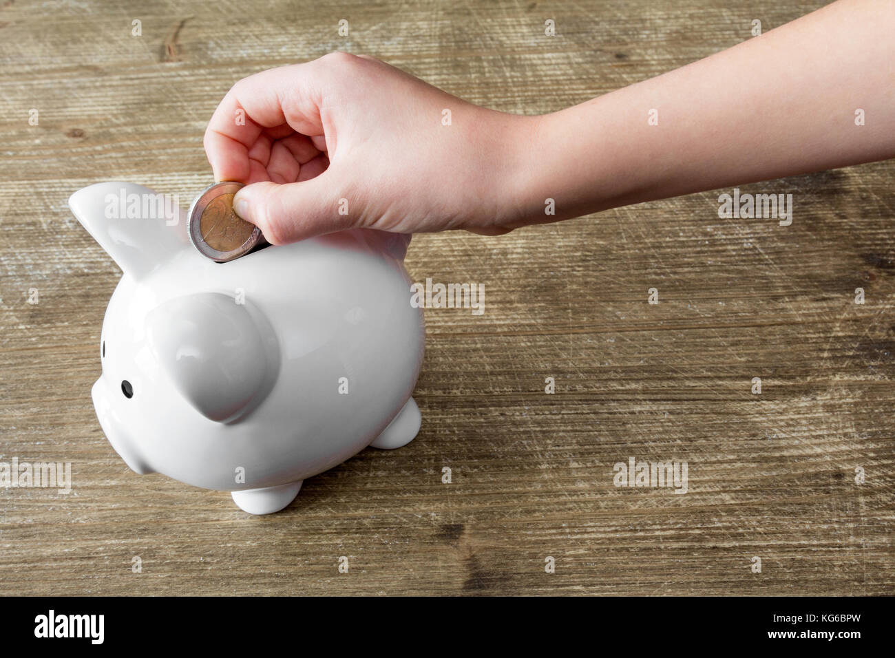Child's hand putting a coin into piggy bank Stock Photo - Alamy