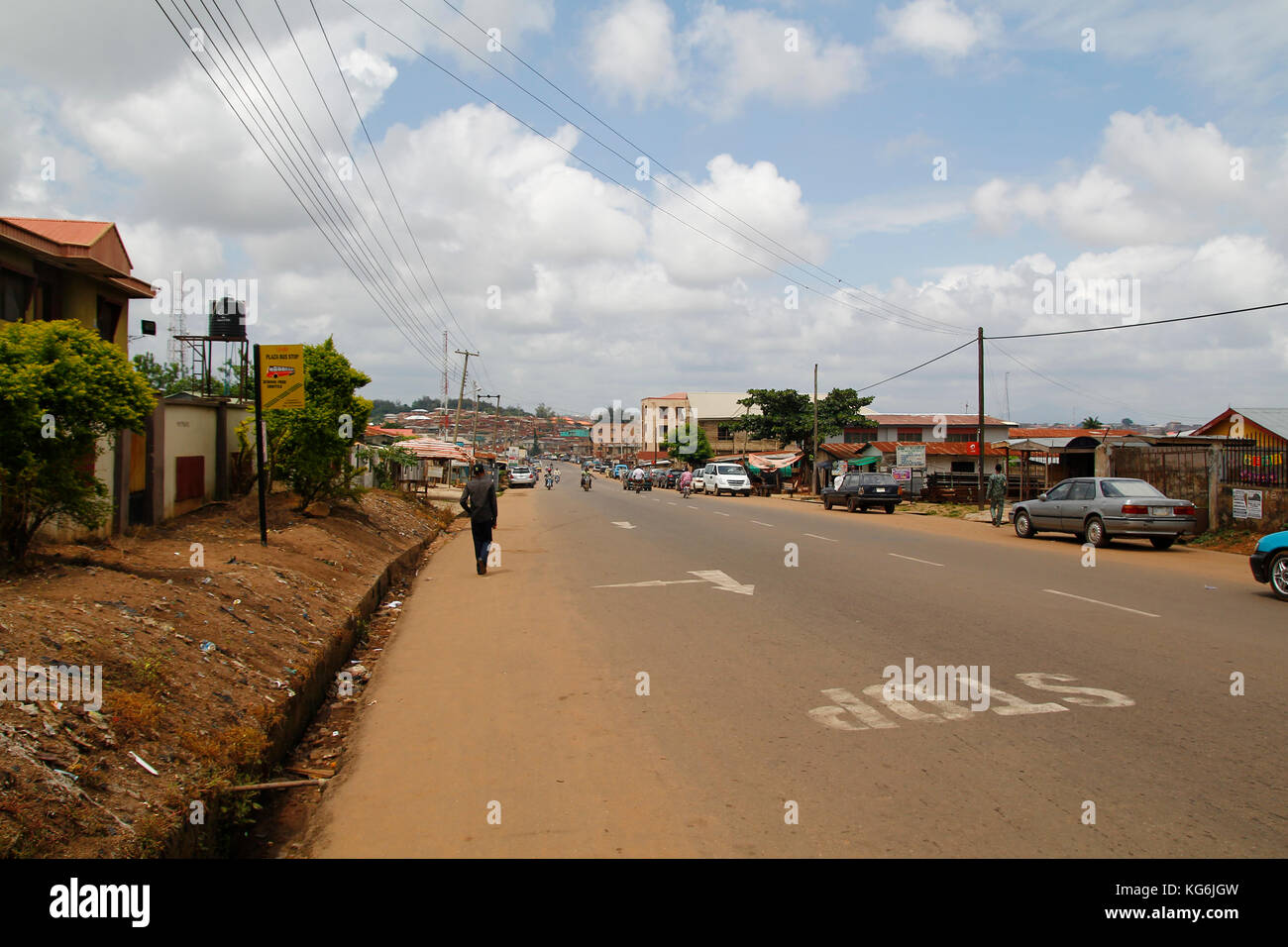 Street wiew of Akure in Ondo state, Nigeria, with cars and people walking next to the houses Stock Photo