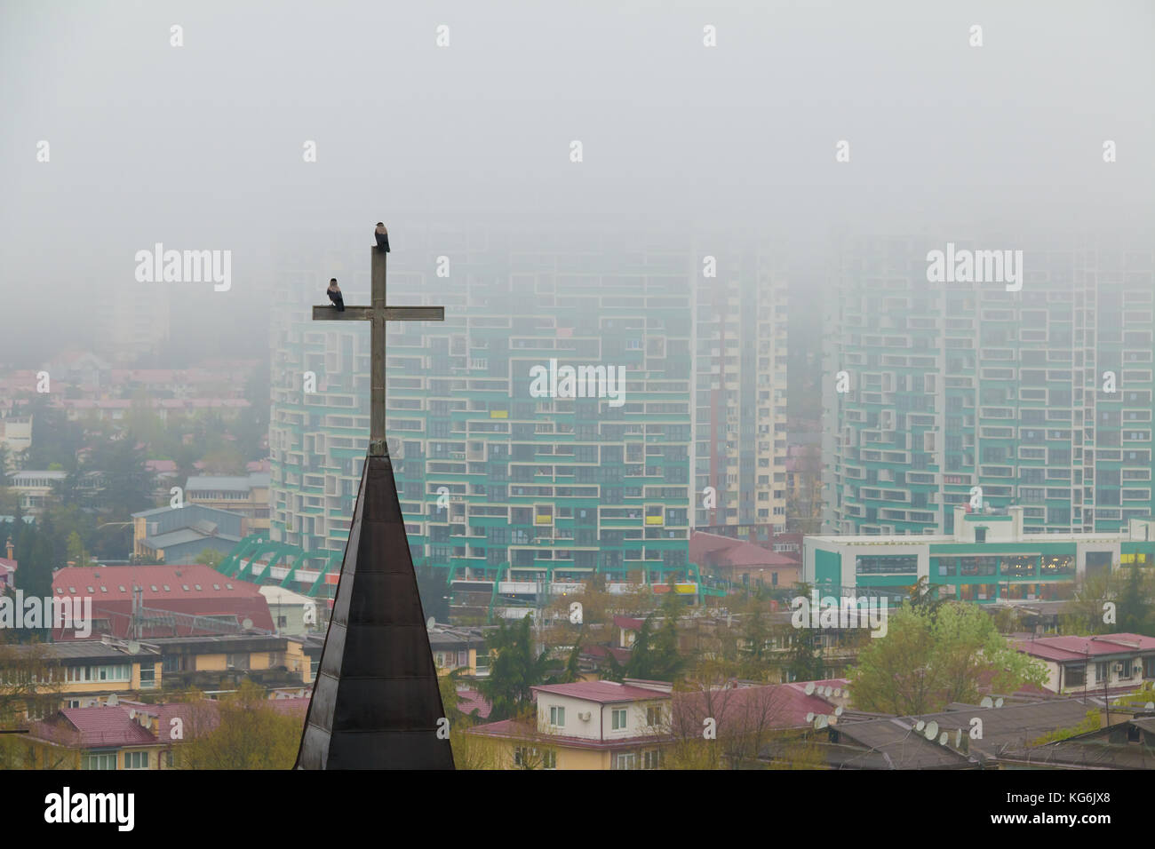 Aerial view of the cross of church on the background of apartment buildings in the morning fog, Sochi, Russia Stock Photo