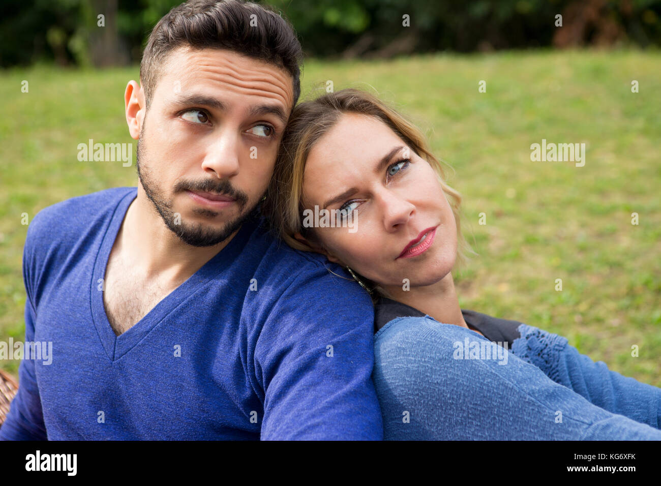 young couple sitting in park leaning against each other Stock Photo - Alamy