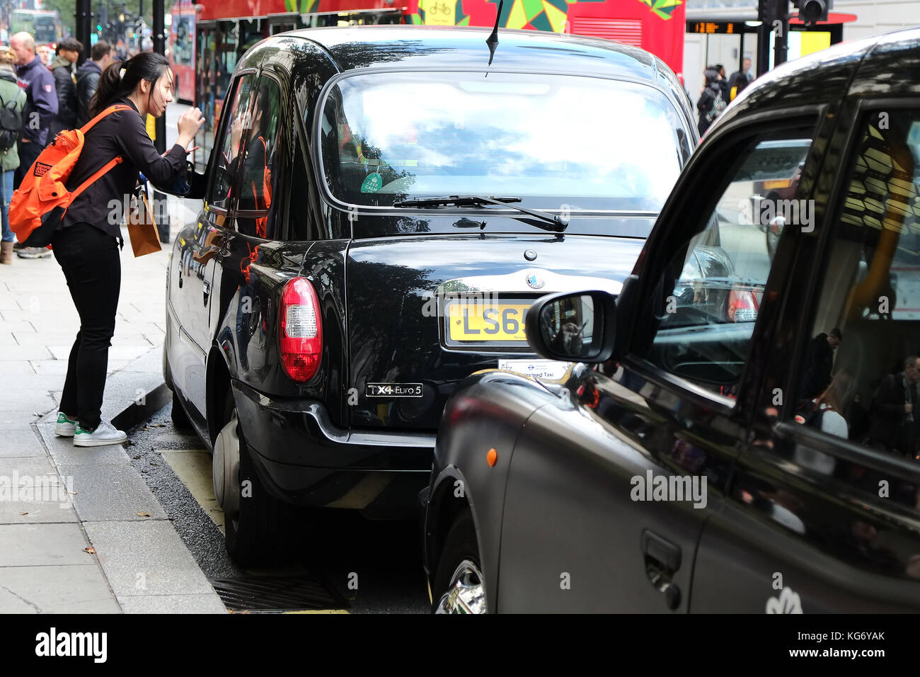 Hailing a traditional Black Cab in London outside Selfridges on Oxford Street Central London UK Stock Photo