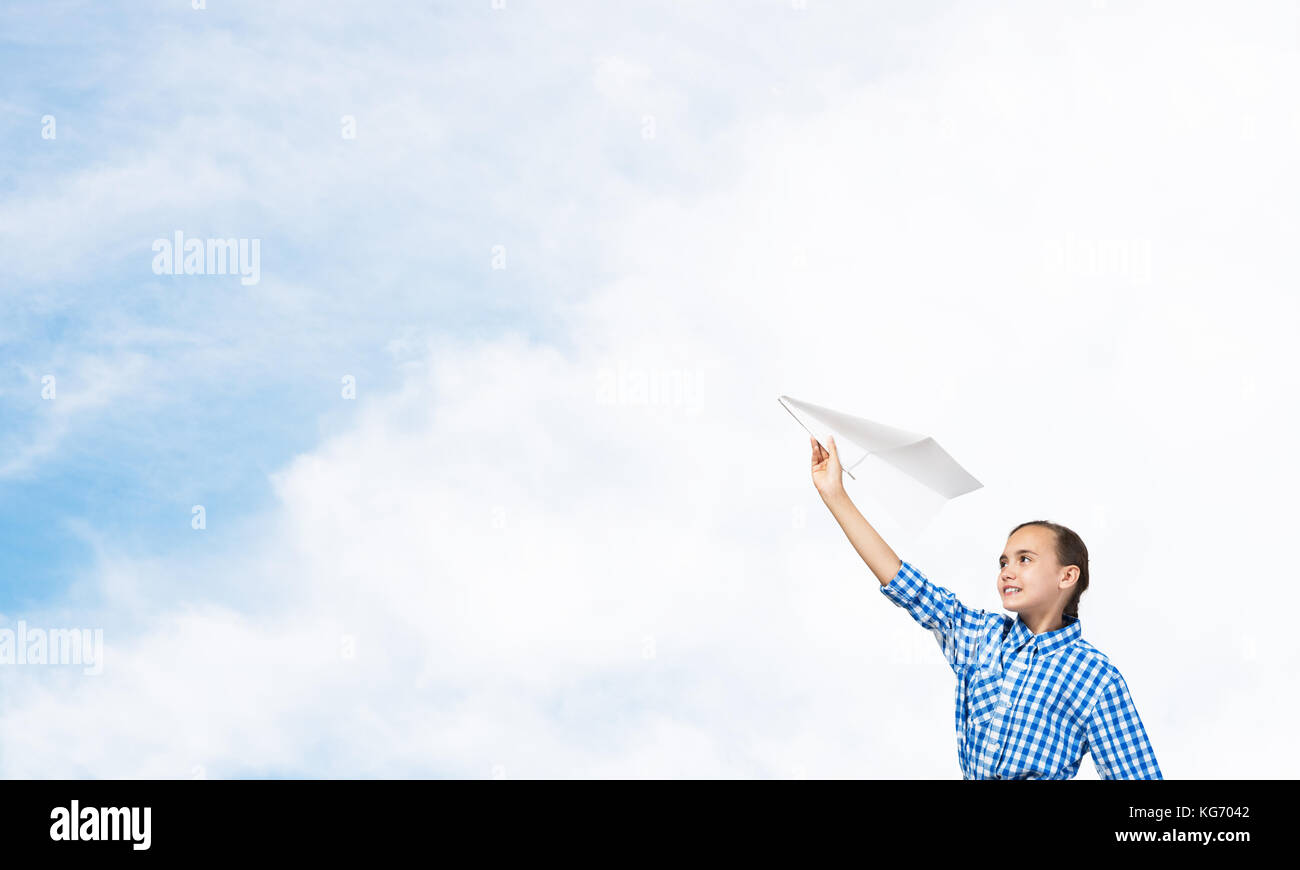Adorable little girl holding paper plane outdoors on blue sky ...