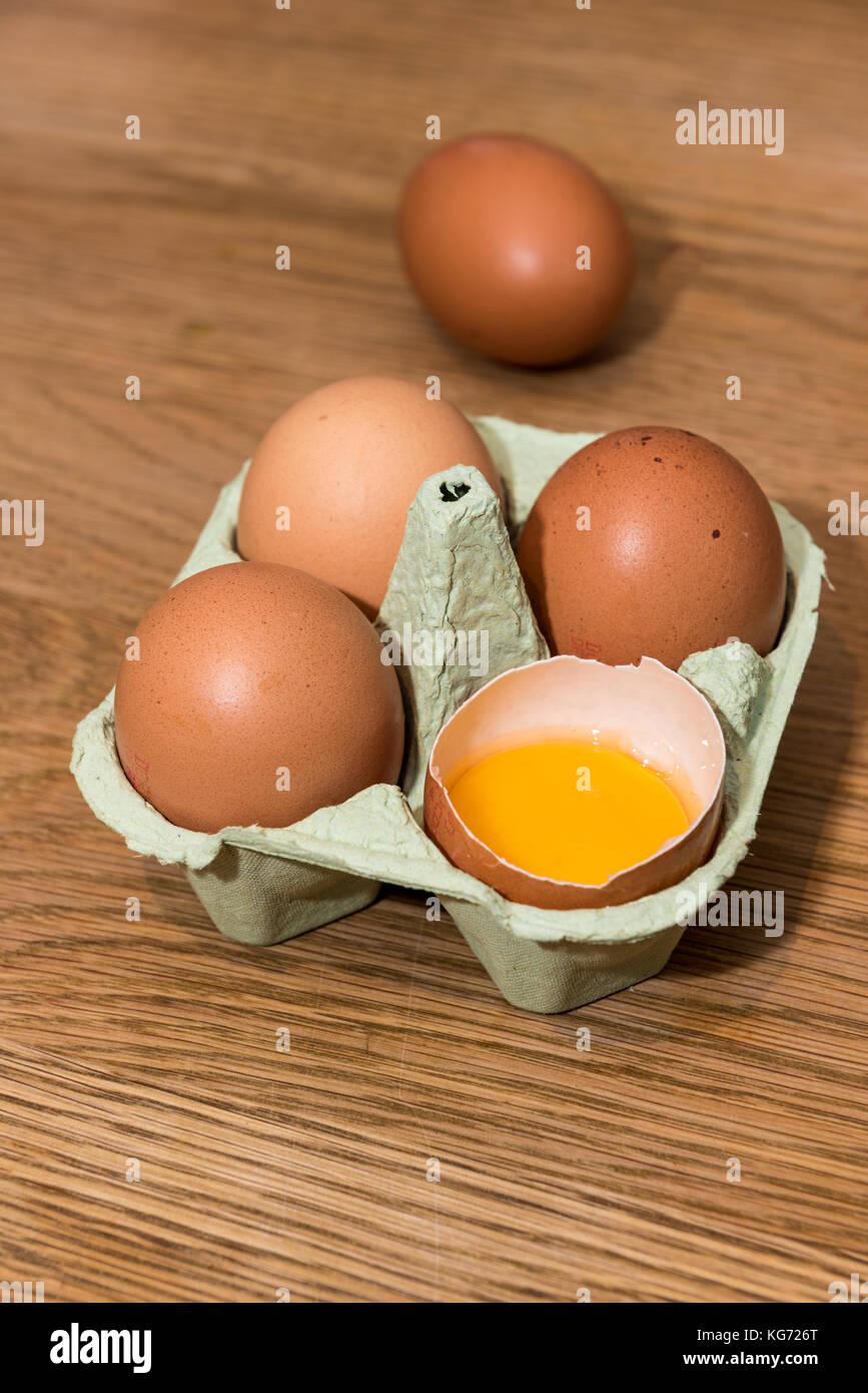 Close-up view of raw chicken eggs in egg box on oak wooden background ...