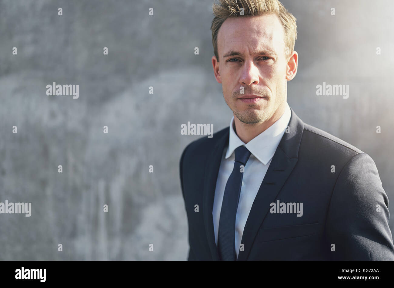 Stylish young businessman wearing suit standing and looking at camera ...